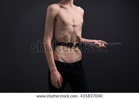 Jovem apertando a cintura com cinto em fundo escuro