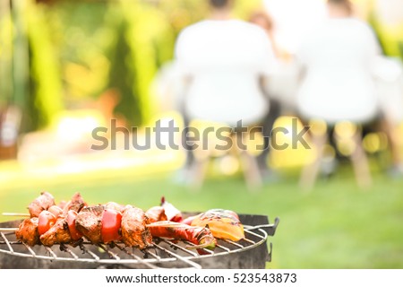 Tasty meat and vegetables on barbecue grill against blurred background, close up view