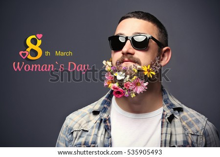 Handsome man in sunglasses with flowers in beard on dark background. Text 8TH MARCH, WOMAN'S DAY