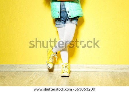 Little African American girl in denim against yellow wall. Fashion concept