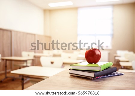 School teacher's desk with stack of books and apple