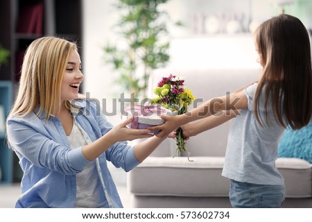 Little girl giving present to her mother at home. Mother's day concept