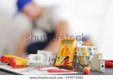 Set of electrician tools and blurred man at work on background