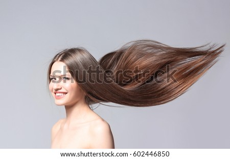 Beautiful young woman with long straight hair on light background