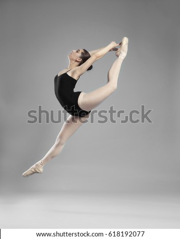 Young beautiful ballerina dancing on light background
