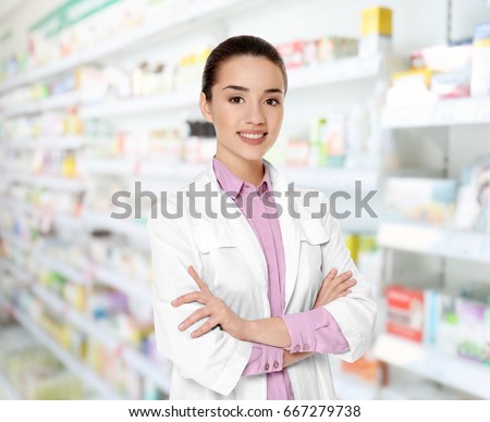 Young female pharmacist at work. Blurred shelves with pharmaceutical products on background