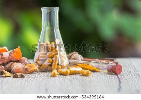 Turmeric powder capsules and erlenmeyer flask with herbal Turmeric powder capsules capsule on wooden background. Turmeric powder capsules use for herbal medicine
