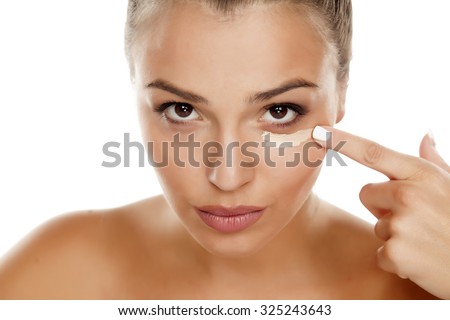 young woman apply concealer under the eye