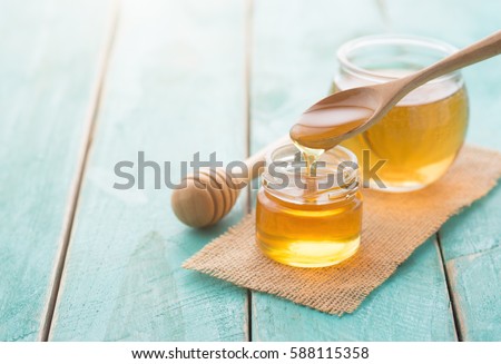 Honey with wooden honey dipper on blue wooden table