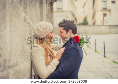 young man giving his girlfriend a rose and kissing celebrating valentines day