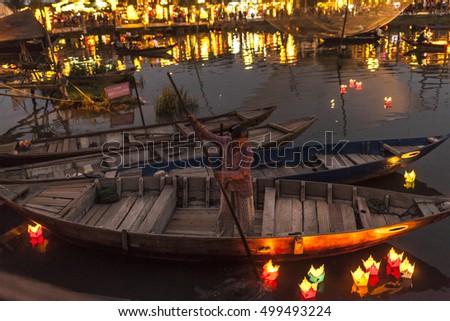 HOI AN, VIETNAM - MARCH 15 2016: Night view of a unidentified vietnamese woman on a boat that waiting for tourist at riverfront of Hoi An old town. Hoi An is declared a World Heritage Site by UNESCO