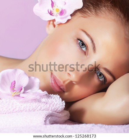 Image of cute young lady enjoying dayspa, closeup portrait of pretty woman with orchid flower in head on pink background, luxury spa resort, healthy lifestyle, beauty treatment and skin care concept