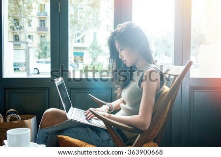 Beautiful young Asian girl working at a coffee shop with a laptop.female freelancer connecting to internet via computer.flare light