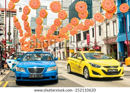 SINGAPORE - FEBRUARY 12, 2015: multicolored taxi cabs driving on South Bridge Road near the corner with Temple Street in Chinatown district with colorful decorations for the upcoming Chinese New Year