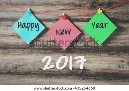 Happy new year 2017 on colorful paper with clothespin hanging on a string with wooden background, retro style