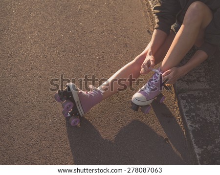 https://thumb1.shutterstock.com/display_pic_with_logo/1448759/278087063/stock-photo-a-young-woman-is-sitting-on-the-ground-and-is-putting-on-roller-skates-in-the-park-at-sunset-278087063.jpg