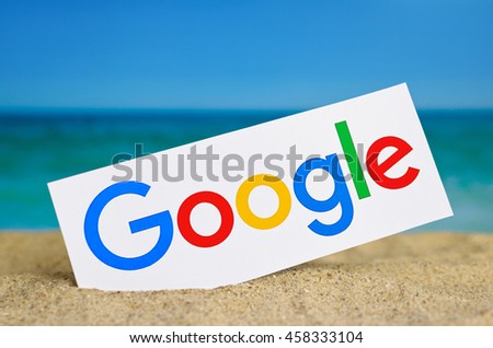 Kiev, Ukraine - June 22, 2016: Logo largest Internet search engine Google printed on paper and placed in the sand against the sea. Google it is the largest Internet search engine, owned of Google.