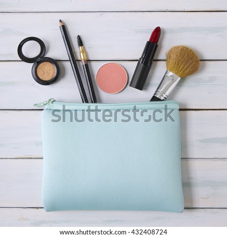 Make-up bag with products spilling out on a wooden background