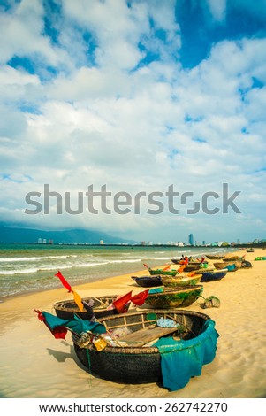 Traditional fishing boats on the beach of Da Nang city, the cityscape and Son Tra peninsulain are visible in distance. Vietnam.