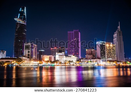 Cityscape of Ho Chi Minh at night with bright illumination of modern architecture, viewed over Saigon river in Southern Vietnam.