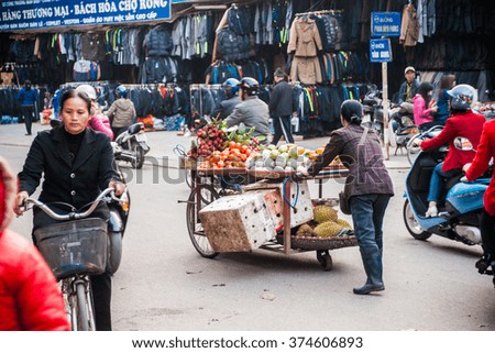 NINH BINH, VIETNAM - JANUARY 23, 2015: A woman in traditional conical hat sells vegetables and fruits in a movable vehicle. Exotic food is one of the main attraction for tourists in Vietnam.