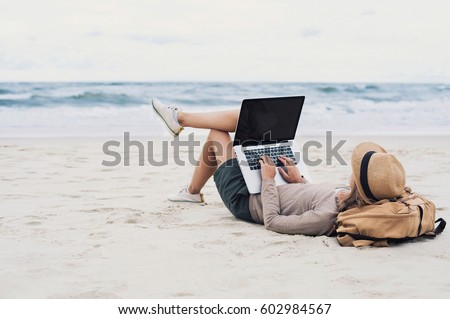 Young woman using laptop computer on a beach. Freelance work concept