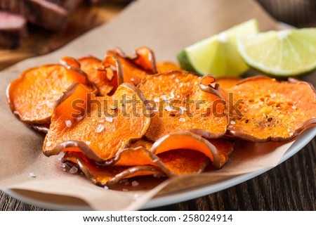 Homemade organic baked pumpkin chips served with lime wedges on kraft paper