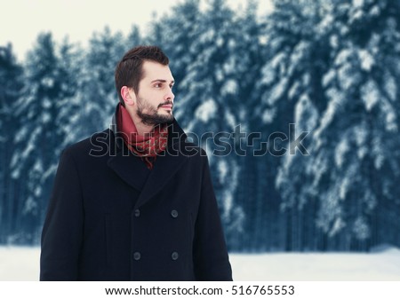 Fashion portrait handsome elegant bearded man wearing black coat in winter day over snowy trees forest background, empty copy space