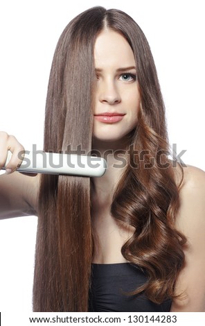Portrait of young beautiful girl using styler on her shining hair