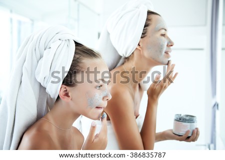 Mother and tween daughter make a clay facial mask, family skin care in the bathroom