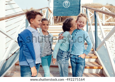 Group of fashion children wearing denim clothing hugging on the sea shore. Autumn casual outfit in blue and navy color. 7-8 years old models.