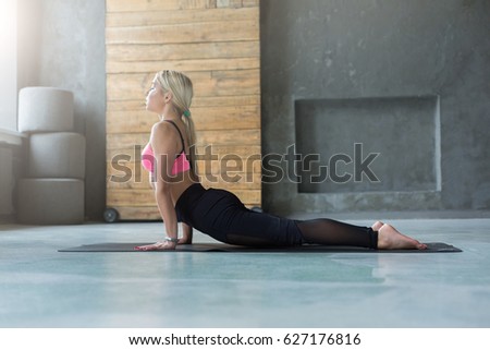 Woman stretching in exercise room, indoors. Full length side view of fit girl in sportswear doing morning gymnastics Woman stretching in exercise room, indoors. Full length side view of fit girl in sportswear doing morning gymnastics