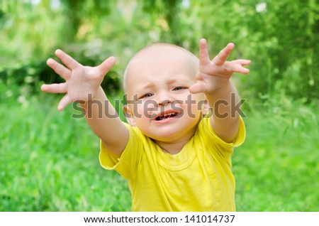 Baby boy reaching towards the viewer in park