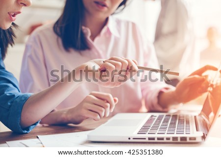 Team work process. Two women with laptop in open space office. Business concept. Film effect and sun glare effect