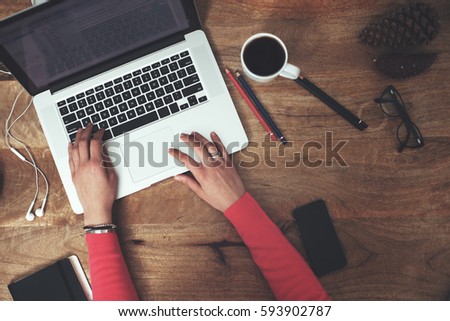 Woman sitting at the office desk with laptop, mobile phone and accessories and typing on computer