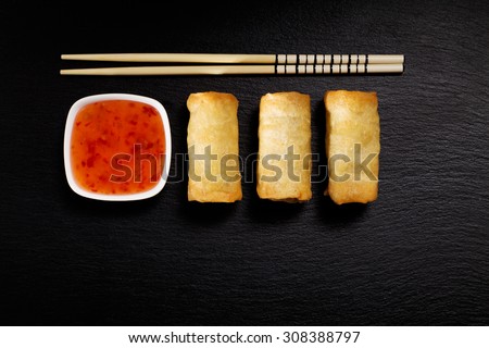 Baked spring rolls with deep, rice and vegetables, on a black plate