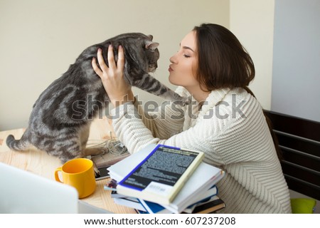 https://thumb1.shutterstock.com/display_pic_with_logo/161514277/607237208/stock-photo-student-holding-her-cat-at-home-sitting-at-the-table-loving-girl-kissing-her-pet-in-a-domestic-607237208.jpg