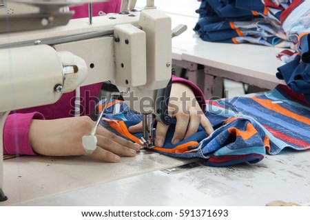 closeup seamstress on the machine sews clothes at a garment factory
