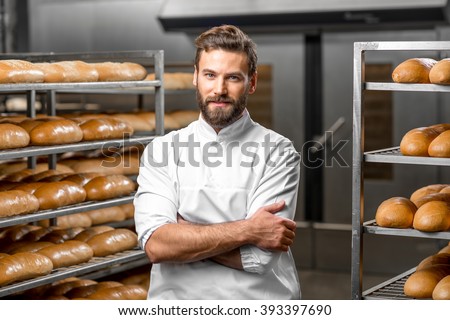 Portrait of handsome baker at the bakery with breads and oven on the background