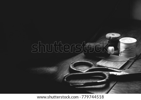 Old sewing machine needle with black thread, on a old grungy work table. Tailor's work table. textile or fine cloth making. industrial fabric, darck background black and white