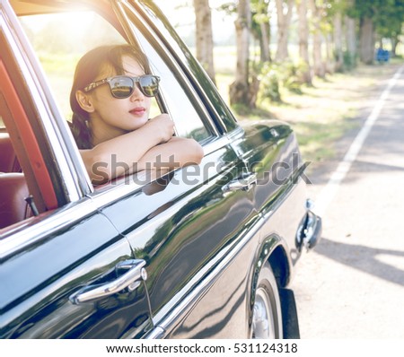 Car woman happy in old retro vintage car. Young woman driving on road trip on beautiful sunny summer day. Pretty mixed race Asian / Caucasian female model.