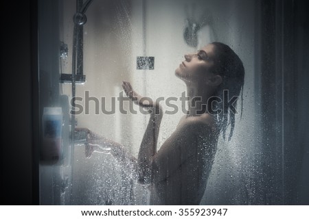Relief and relaxation after long stressful day.Taking moment for yourself concept.Skincare,spa and aromatherapy.Unfocused portrait of a woman showering through the bath screen with little drops