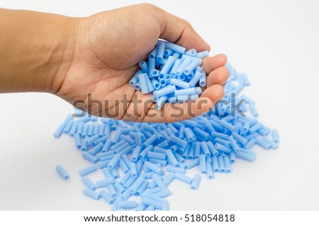 Isolated of Blue plastic bead in human hand on white background