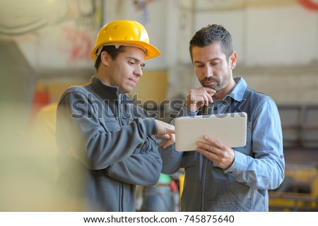 contemplative manual workers looking at digital tablet