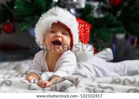 Adorable baby laughing near the Christmas three