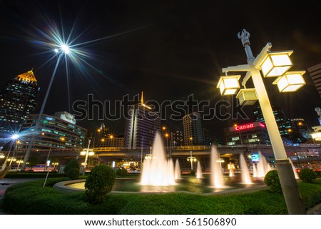 Downtown of Bangkok from an entrance of Lumphini park by road Rama IV and a skytrain railway at night , skyscrapers and canon logo , January 16 2017