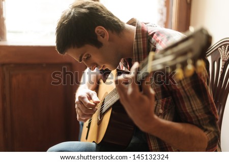 Practicing in playing guitar. Handsome young men playing guitar