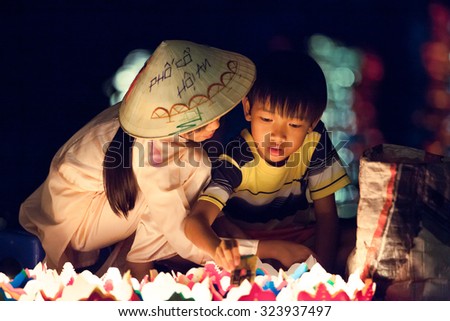 Hoi An, Vietnam - March 14, 2014: Vietnamese girl and boy are selling candles for tourists in Hoi An old town at night on March 14, 2014 in Hoi An, Vietnam.