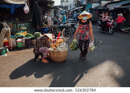 Nha Trang, Vietnam - July 14, 2016: Vietnamese woman in conical hat walks at the morning market in Nha Trang, Vietnam on July 14, 2016.