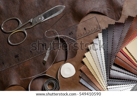 Crafting tools on natural cow leather in the tailoring workshop. Top view.